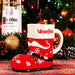 Red Santa boot mug with 'Wauwatiки' branding next to a bottle of Ketel One Vodka against a festive background.