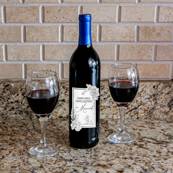 Wine bottle with a label and two glasses of red wine on a countertop.