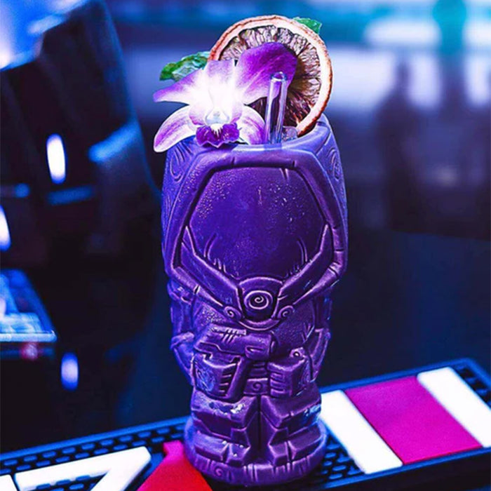 Purple cocktail in a warrior-themed glass with garnishes on a blurred bar background