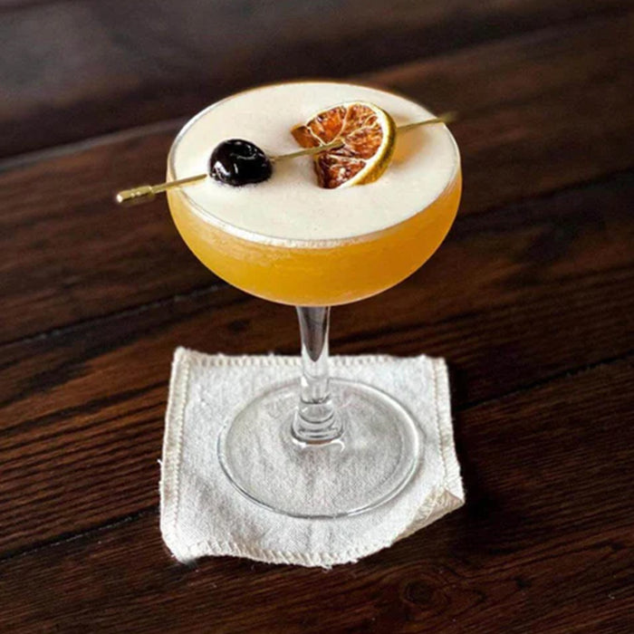 Cocktail with a cherry and orange slice on a wooden surface