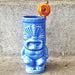 Blue ceramic tiki mug with a decorative top on a concrete surface