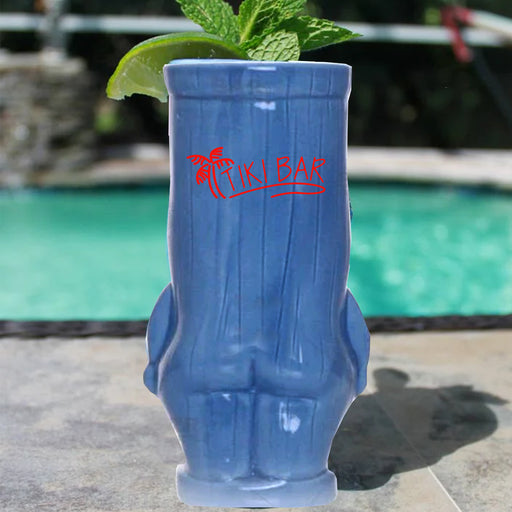 Blue tiki mug with 'Tiki Bar' logo and mint leaves by a pool