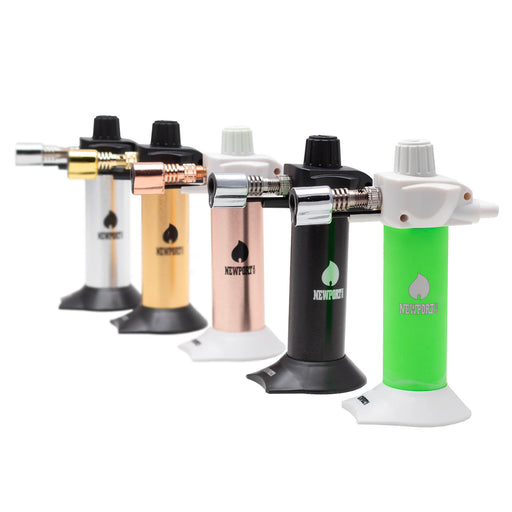 Five portable torch lighters in different color options (silver, gold, rose gold, and black) lined up in a row on a white background. Each lighter features a cylindrical body with a flame adjustment knob on top and a base stand.