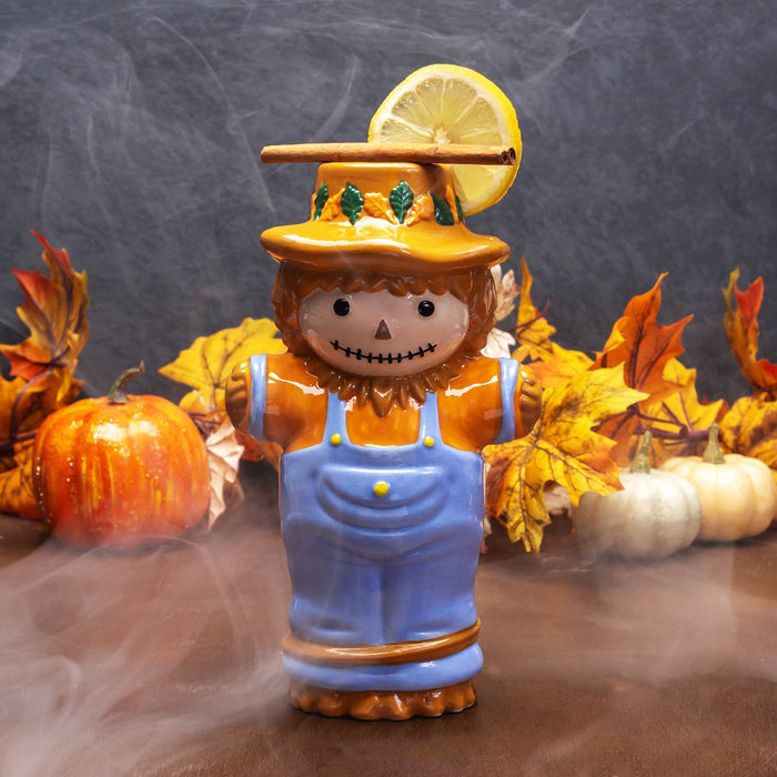 Scarecrow tiki mug with autumn decorations on a dark background
