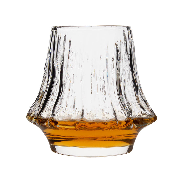 Clear glass tumbler with a textured base filled with amber liquid on a white background