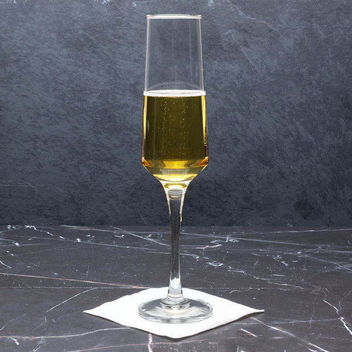 Champagne flute with golden liquid on a dark marble surface