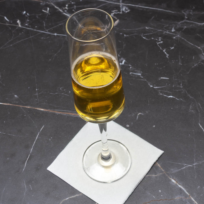 Glass of yellow liquid on a dark marble surface
