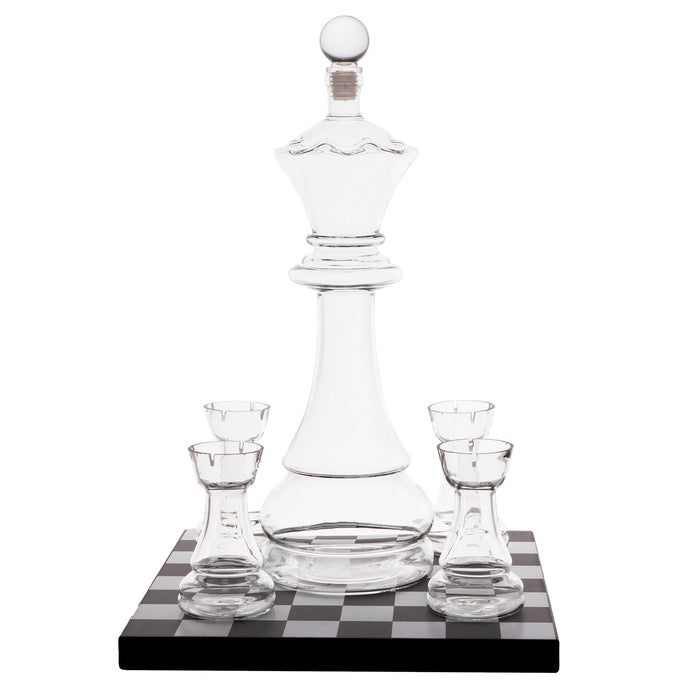 Clear glass chess-piece-shaped decanter with four matching small glasses, displayed on a black-and-white checkered base against a white background.