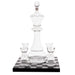 Clear glass chess-piece-shaped decanter with four matching small glasses, displayed on a black-and-white checkered base against a white background.