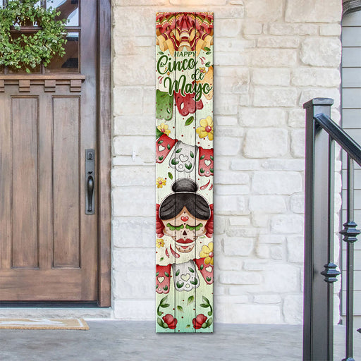 Decorative sign with 'Happy Cinco de Mayo' text on a vertical board against a stone wall.