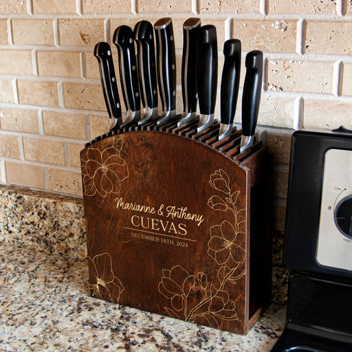 Wooden knife block with engraved names and dates on a kitchen counter.