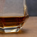Glass of amber liquid on a wooden surface with a blurred background