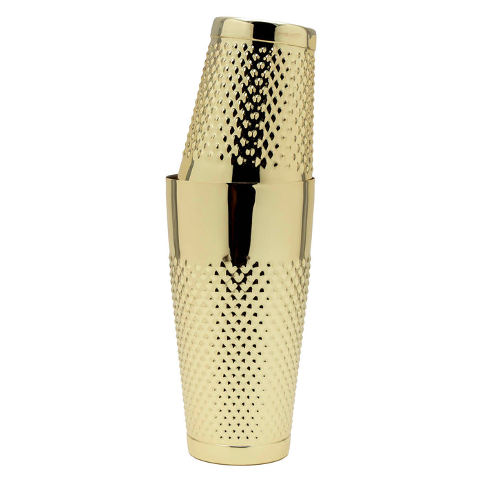 A polished gold cocktail shaker with a textured, diamond-patterned body, shown stacked with a matching gold lid on a plain white background.