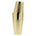 A polished gold cocktail shaker with a textured, diamond-patterned body, shown stacked with a matching gold lid on a plain white background.