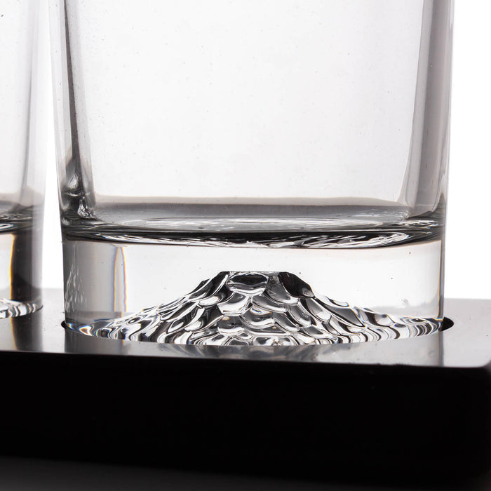 Clear glass rocks glasses with a sculpted mountain base, shown on a black surface with a white background.