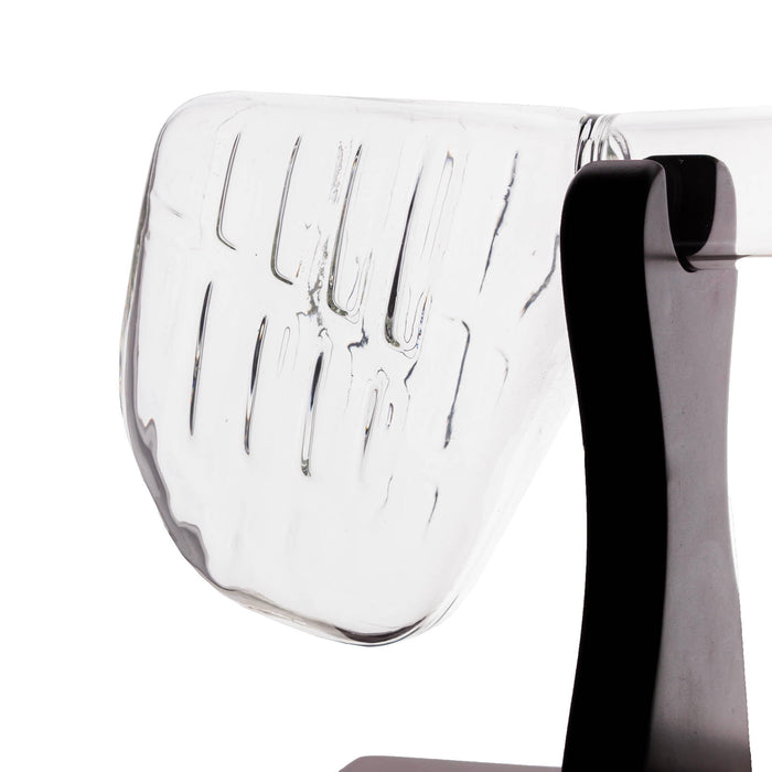 A close-up of a modern transparent glass chair with a ribbed clear backrest and a black metal side support, shown against a plain white background.