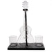 A clear glass acoustic guitar-shaped decanter with a black base, shown on a white background with two small clear glasses on either side of the base.