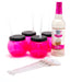 Pink drink containers with black lids, straws, and a bottle of Skinny Mixes White Chocolate syrup on a white background.