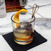 Glass of whiskey with an orange twist on a marble surface