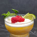 Glass of yellow drink with raspberries and lime on a dark background