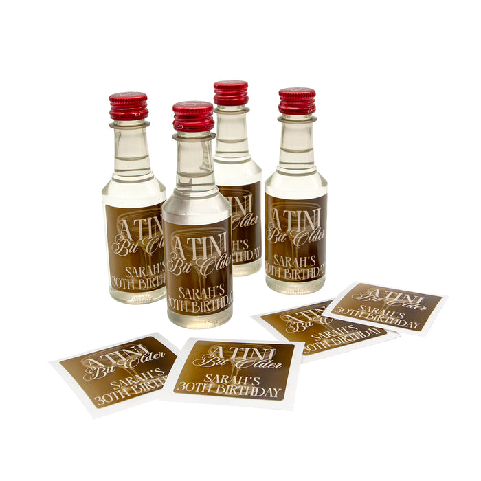 Set of mini bottles with red caps and personalized labels on a white background