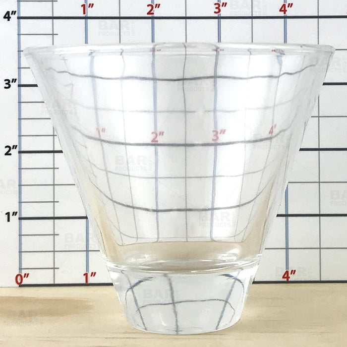 Clear glass cup with grid lines against a ruler background