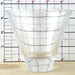 Clear glass cup with grid lines against a ruler background
