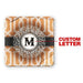 Square coaster with geometric pattern and central 'M' design, featuring a custom letter feature.